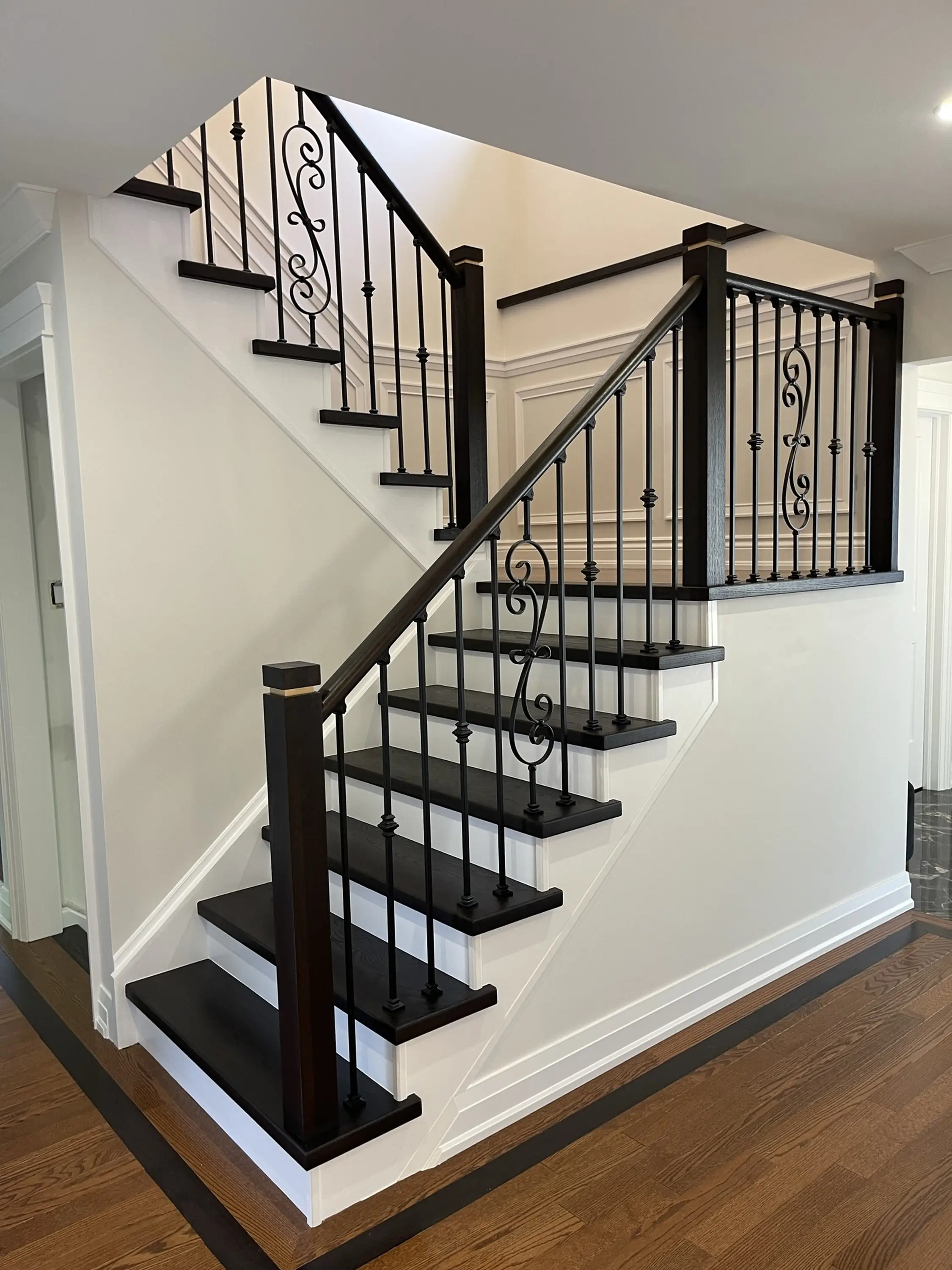 Grand curved staircase with custom wrought iron railings in an upscale Toronto home.