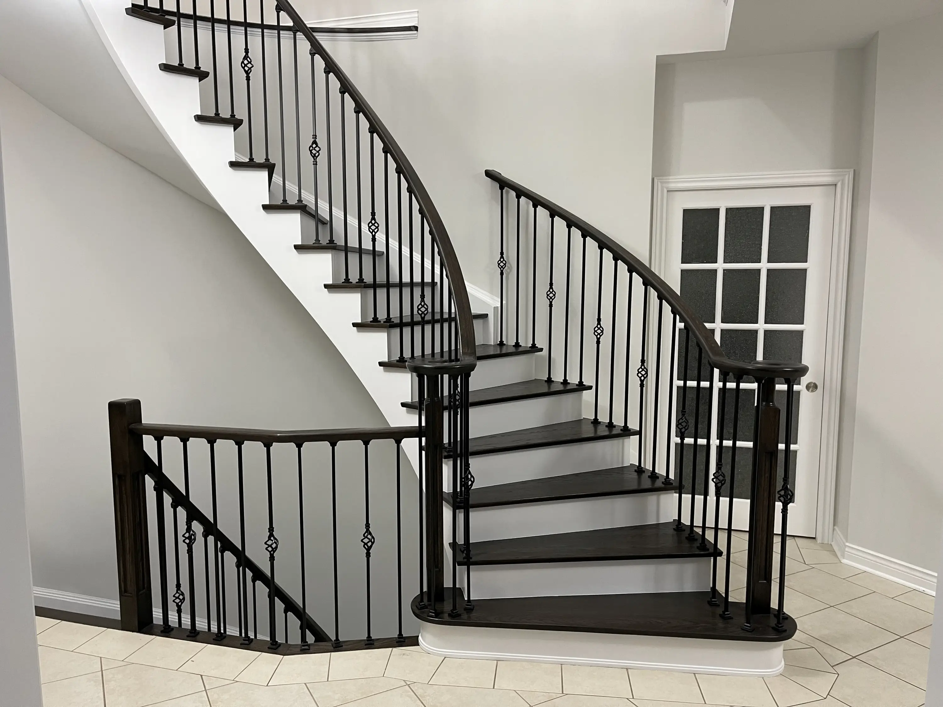 Newly renovated staircase with white risers, hardwood treads, and decorative custom railings.