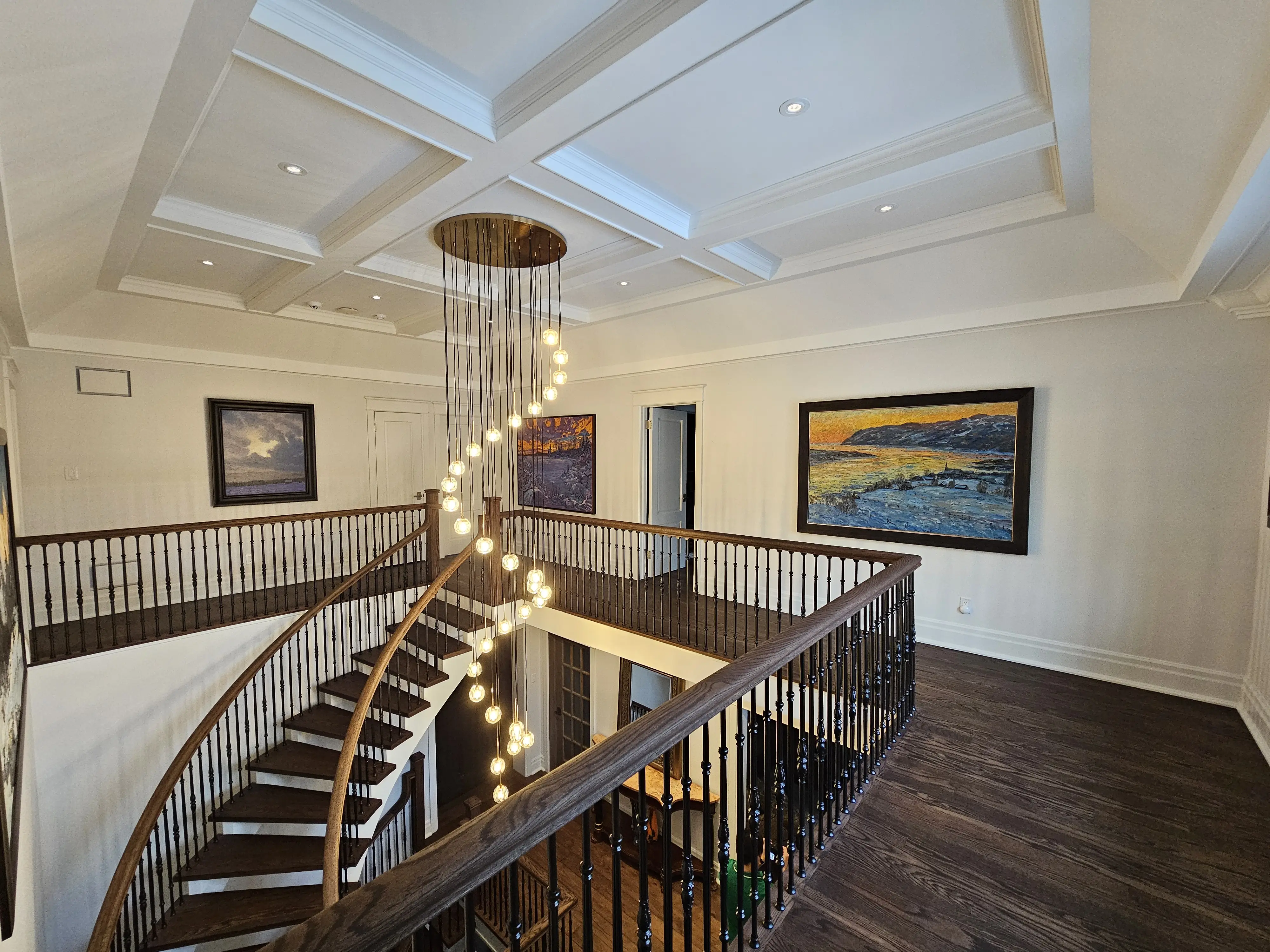Curved interior staircase with oak treads, white risers, and custom iron railings renovated by Strataline in Vaughan.