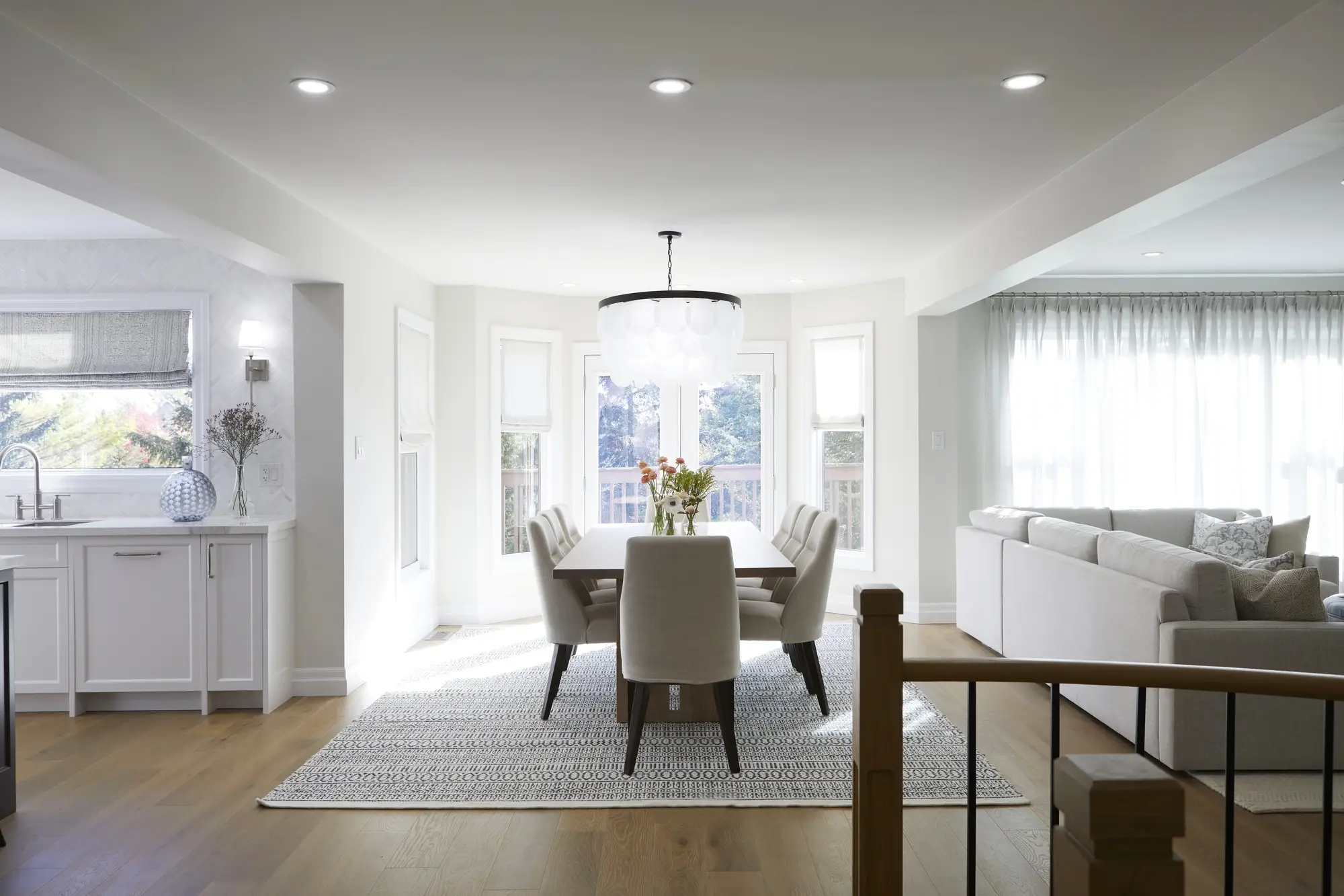 A spacious dining room, beautifully renovated, featuring a long table surrounded by numerous chairs and a vibrant plant centerpiece that adds warmth.
