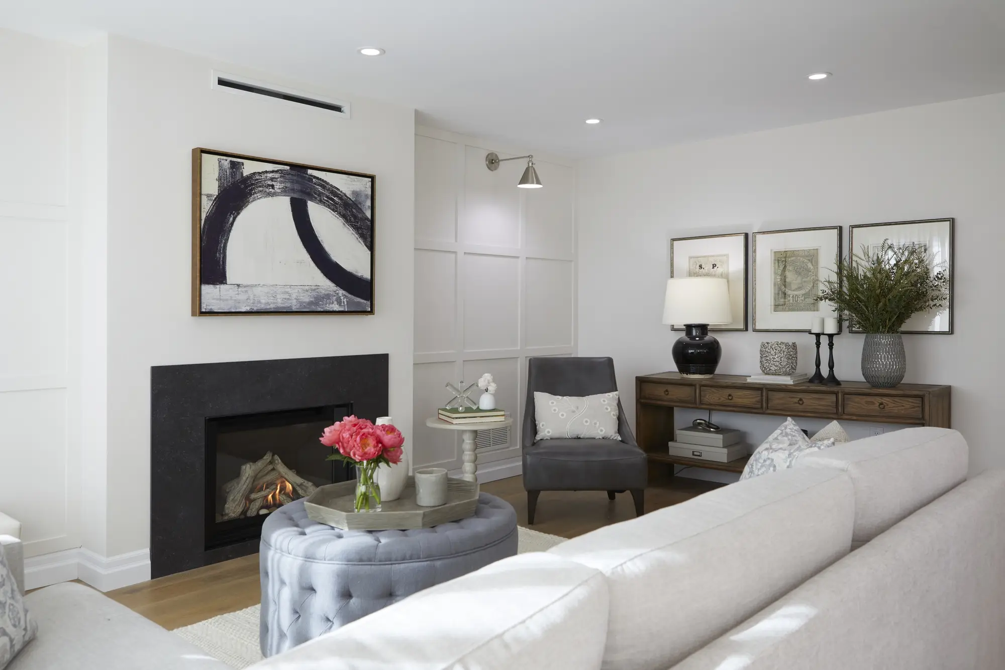 A renovated updated living room with a charming fireplace, featuring an L-shaped couch, a small side table for decor, and an additional compact couch for extra seating.